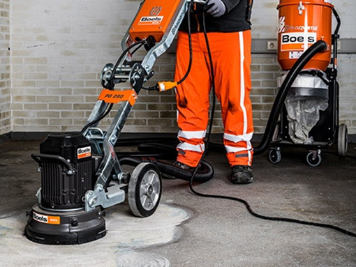 Man sands floor with concrete sander